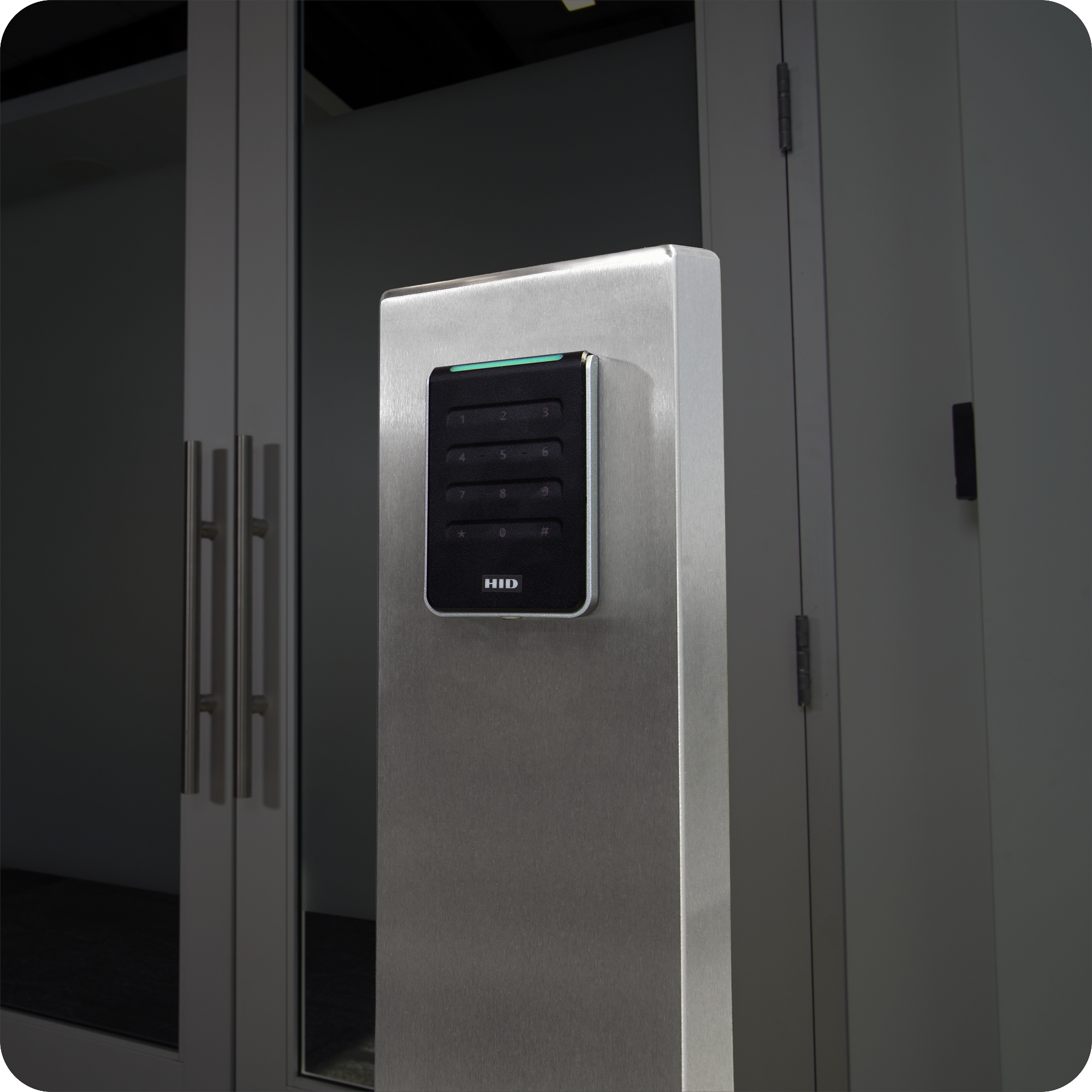Stainless steel pedestal with keypad in a glass lobby entrance